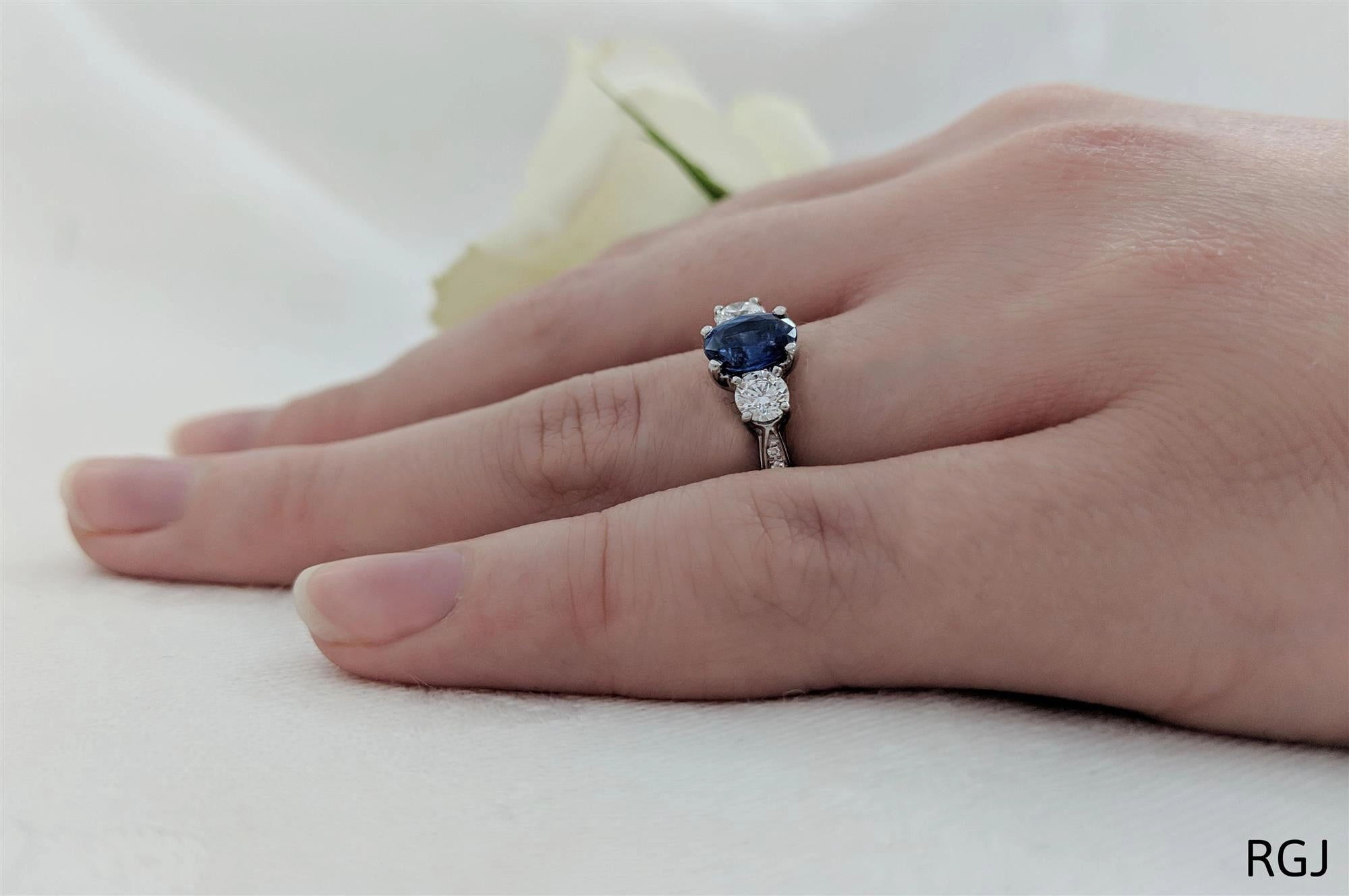 The Memoire Platinum 0.98ct Oval Cut Blue Sapphire And 0.55ct Diamond Three Stone Engagement Ring With Diamond Set Shoulders