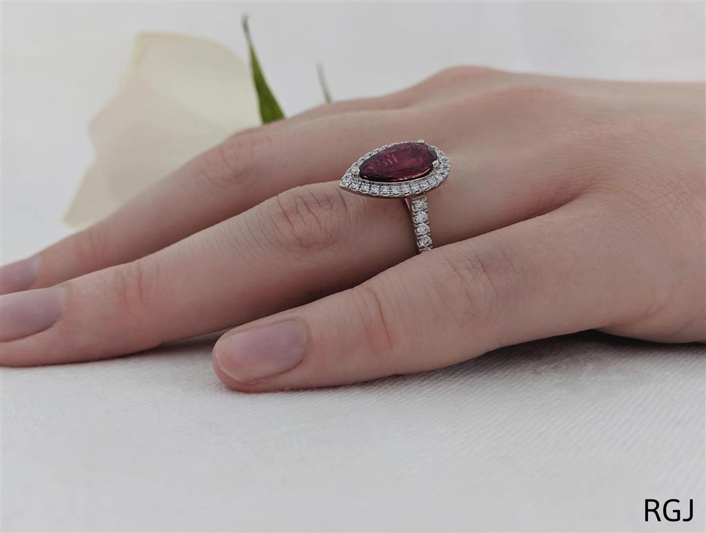The Skye Platinum 1.92ct Pear Cut Ruby Ring With 0.44ct Diamond Halo And Diamond Set Shoulders