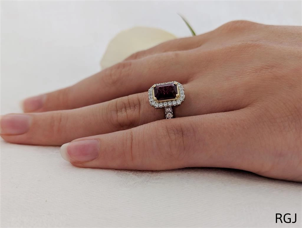 The Skye Platinum And 18ct Yellow Gold 1.15ct Emerald Cut Ruby Ring With 0.41ct Diamond Halo And Diamond Set Shoulders