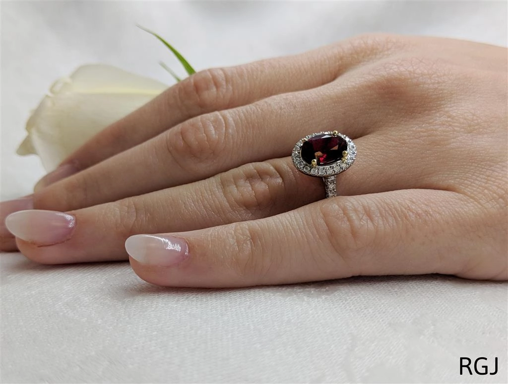 The Skye Platinum And 18ct Yellow Gold 2.13ct Oval Cut Ruby Ring With 0.42ct Diamond Halo And Diamond Set Shoulders
